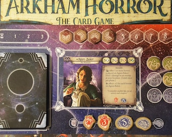 May include: Arkham Horror The Card Game player board featuring a character card for Agnes Baker, the Waitress. The board includes a deck of cards, four hexagonal resource tokens, four green circular tokens, and four damage and horror tokens.