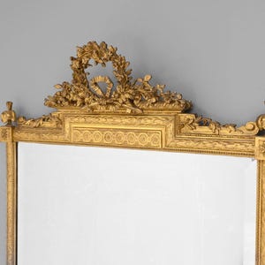 May include: A gold-toned ornate mirror with a decorative floral design at the top and a rectangular frame.