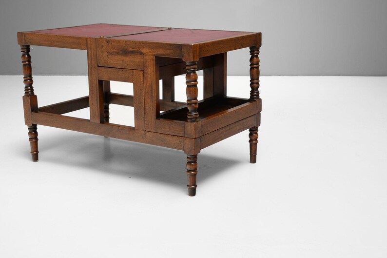 Puede incluir: Una mesa de madera marr&oacute;n oscuro con tapa de cuero rojo. La mesa tiene patas torneadas y un estante inferior. La mesa mide aproximadamente 76 cm de largo, 46 cm de ancho y 51 cm de alto.