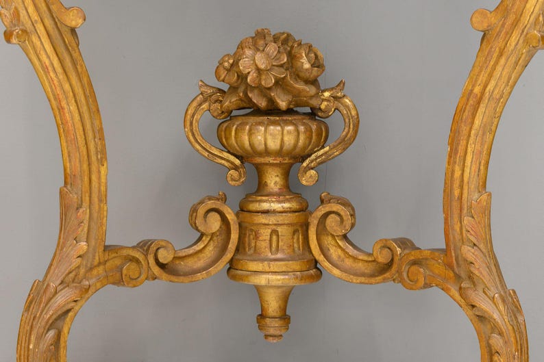 Peut inclure: Une base de table en bois peinte en or avec des sculptures orn&eacute;es et un motif floral. La base est en forme de vase avec deux poign&eacute;es et un dessus rond.