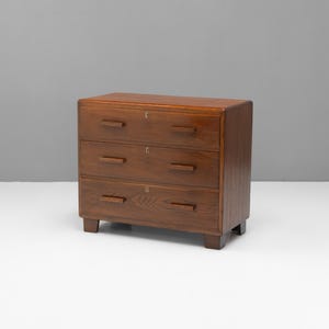 Puede incluir: Un aparador de madera de tres cajones con un acabado marrón cálido. El aparador tiene forma rectangular con bordes redondeados y pequeños tiradores rectangulares. Los cajones están todos cerrados.