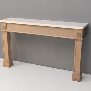 May include: A light-coloured wooden console table with a rectangular white marble top. The table has two square columns on each side and a rectangular base. The table is approximately 152 cm long.