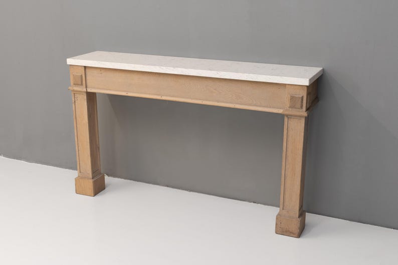 May include: A light-coloured wooden console table with a rectangular white marble top. The table has two square columns on each side and a rectangular base. The table is approximately 152 cm long.