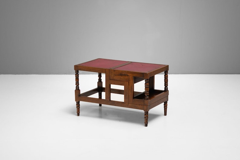 Puede incluir: Una mesa auxiliar de madera oscura con tapa de cuero rojo. La mesa tiene forma rectangular con patas torneadas y un estante inferior. La mesa mide aproximadamente 76 cm de largo, 46 cm de ancho y 61 cm de alto.