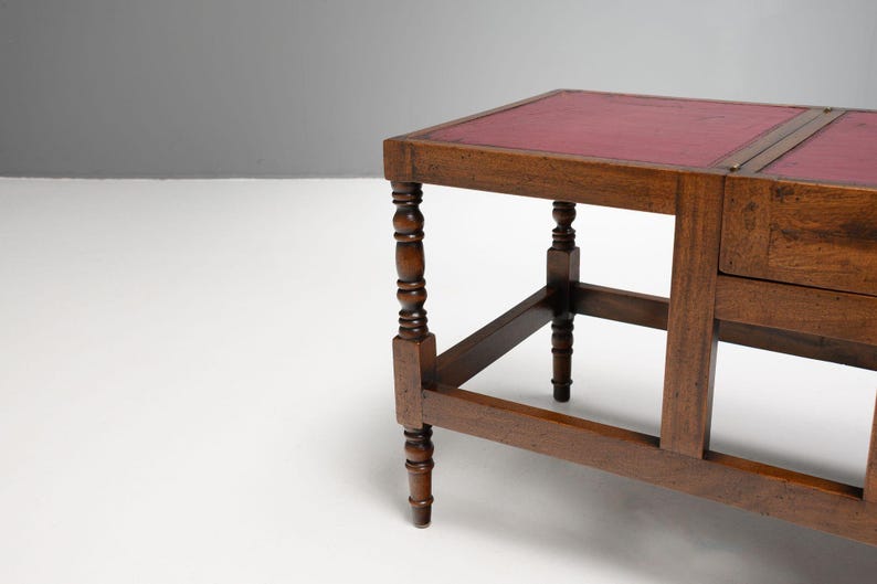 Puede incluir: Una mesa auxiliar de madera con tapa de cuero rojo. La mesa tiene patas torneadas y un caj&oacute;n. La mesa es de madera oscura y tiene un dise&ntilde;o cl&aacute;sico. La mesa mide aproximadamente 76 cm de largo.