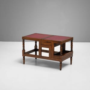 Puede incluir: Una mesa auxiliar de madera con tapa de cuero rojo. La mesa tiene patas torneadas y un estante inferior. La mesa mide 76 cm de largo, 46 cm de ancho y 51 cm de alto.