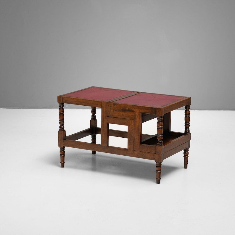 Puede incluir: Una mesa auxiliar de madera con tapa de cuero rojo. La mesa tiene patas torneadas y un estante inferior. La mesa mide 76 cm de largo, 46 cm de ancho y 51 cm de alto.