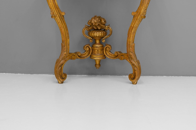 Peut inclure: Une console en bois peinte en or avec des sculptures orn&eacute;es et un fleuron d&eacute;coratif en forme d'urne.