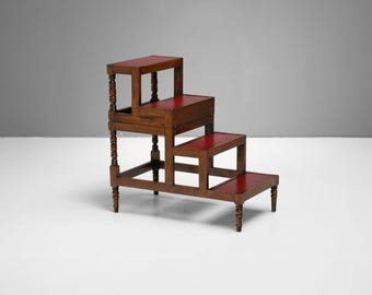 May include: A three-tiered wooden step stool with red surfaces. The dark brown stool has decorative turned legs. The design is similar to a small library step stool, with each step a different height.