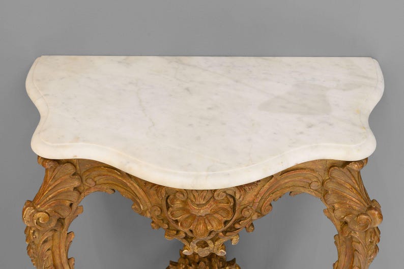 Peut inclure: Une console avec un plateau en marbre blanc et des pieds en bois sculpt&eacute;s et peints en or.