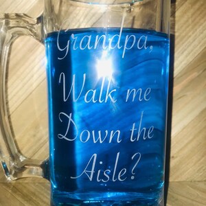 Puede incluir: Una jarra de cerveza de vidrio transparente con un líquido azul en su interior. La jarra está grabada con el texto "Grandpa, Walk me Down the Aisle?"