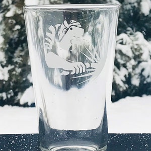 May include: A clear glass pint glass with an etched design of a welder wearing a welding mask and holding a welding torch.