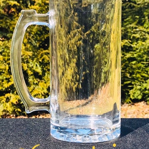 May include: A clear glass 26 ounce stein with a handle. The stein is sitting on a black surface.