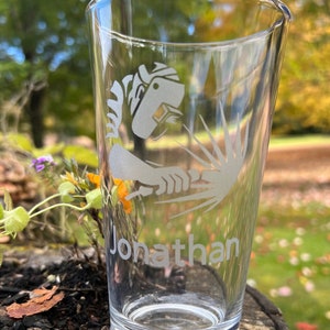 May include: A clear glass beer stein with a white etched design of a person welding. The name "Jonathan" is etched below the design.