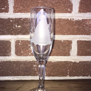 Puede incluir: Una flauta de champán de vidrio transparente con un diseño grabado de una novia con un vestido de novia.