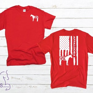 May include: Red t-shirts with white Appaloosa horse designs. One shirt has a small horse graphic on the front, the other has a larger design on the back with an American flag theme and the word "Appaloosa".