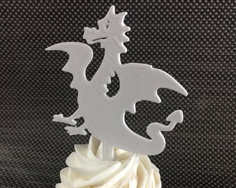 May include: A white cupcake with white frosting topped with a white 3D printed dragon cupcake topper.