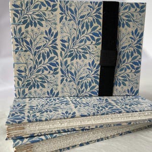 Floral watercolour sketchbook. Coptic binding with 300gsm cold pressed paper. Front view of a collection of A5 landscape books with elastic holders.