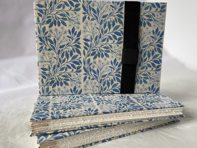 Floral watercolour sketchbook. Coptic binding with 300gsm cold pressed paper. Front view of a collection of A5 landscape books with elastic holders.