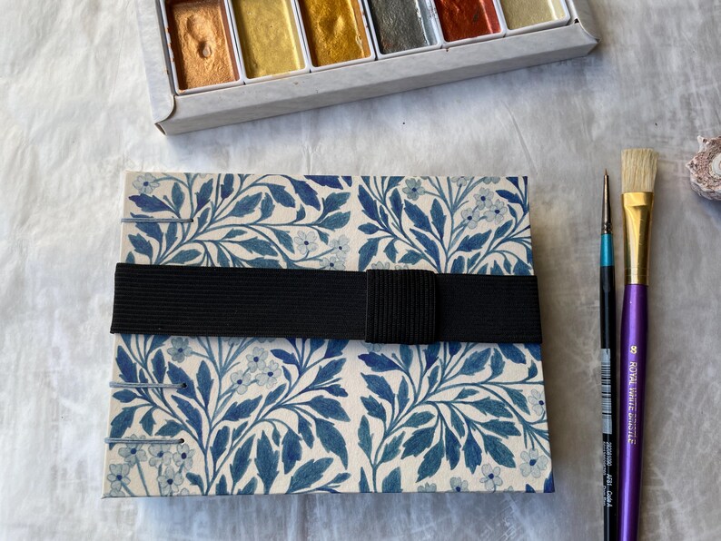 Floral watercolour sketchbook. Coptic binding with 300gsm cold pressed paper. Front view of A6 landscape book with elastic tie.
