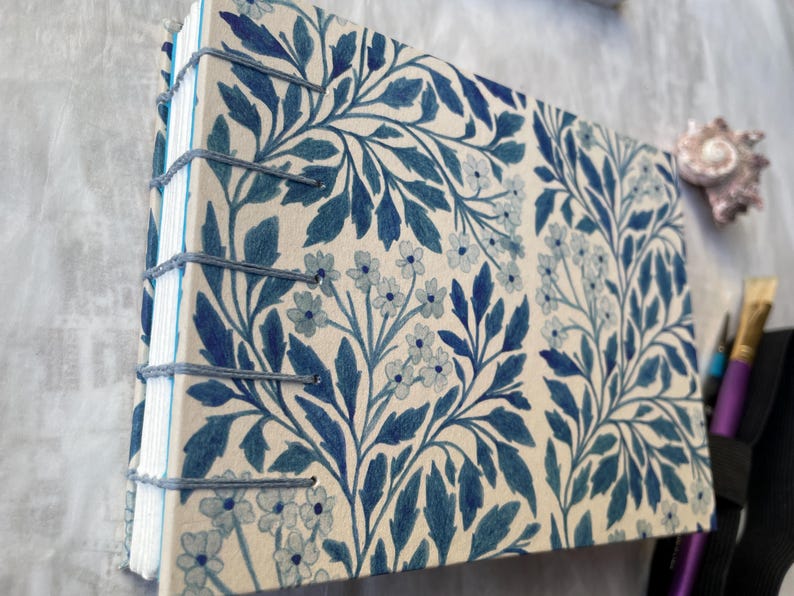 Floral watercolour sketchbook. Coptic binding with 300gsm cold pressed paper. Front and spine view of A6 landscape book.