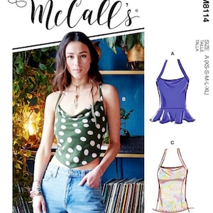May include: A sewing pattern for a halter top with a cowl neck. The pattern includes three different styles: a purple top with a ruffle, a green polka dot top, and a floral print top. The pattern is for sizes XS-S-M-L-XL. The pattern number is M8114.