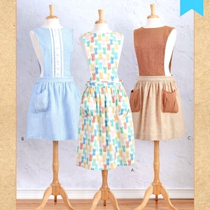 May include: Three different styles of aprons on dress forms. The aprons are all different colors and patterns. The apron on the left is blue and white striped with a white lace trim. The apron in the middle is white with a pineapple pattern. The apron on the right is brown with a tan pocket. The text "MISSES' APRONS" is at the bottom of the image.