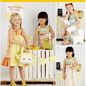 May include: Simplicity pattern 8145 features children's dresses and accessories. The image shows girls wearing dresses with floral and polka dot patterns. One girl holds a purse shaped like a face. The background includes lemonade stand decorations.