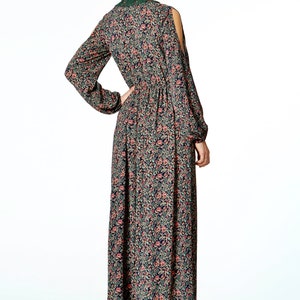 May include: A long, floral-print dress with long sleeves and shoulder cutouts. The dress features a dark background with a pattern of pink and green flowers. The dress has a cinched waist and a flowing skirt. The neckline is trimmed with green lace.