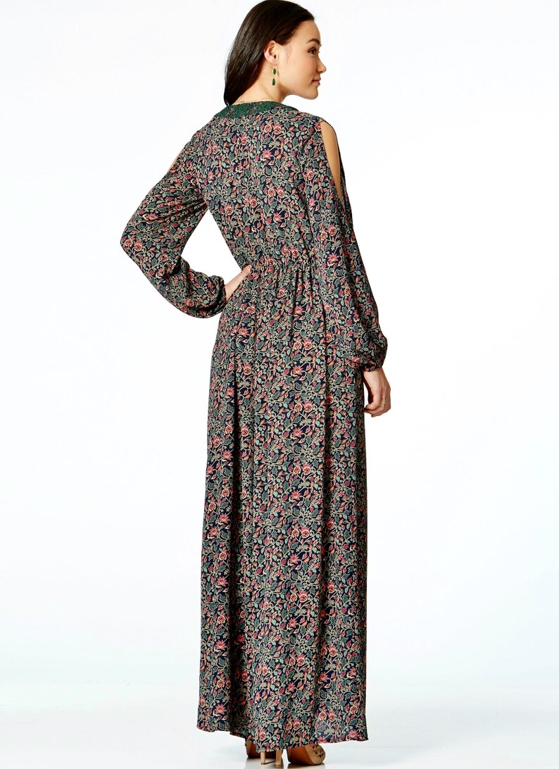 May include: A long, floral-print dress with long sleeves and shoulder cutouts. The dress features a dark background with a pattern of pink and green flowers. The dress has a cinched waist and a flowing skirt. The neckline is trimmed with green lace.
