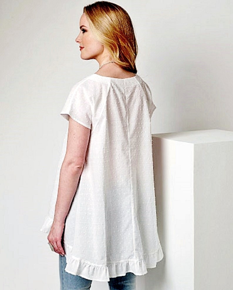 May include: White cotton top with a ruffled hem and short sleeves. The top has a scoop neck and a dotted pattern.
