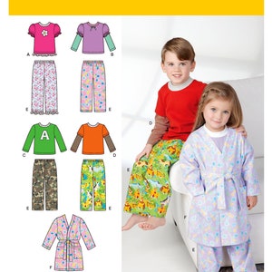 May include: Simplicity pattern 1573 features children's sleepwear designs. The image shows various pajama tops, pants, and a robe. The tops include long and short sleeves, with floral and lettered details. The pajama pants have floral, animal, and camouflage prints. A child models a robe and pajamas.
