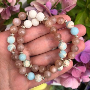 May include: Two bracelets featuring brown, beige, and blue beads. The bracelets are crafted from natural stones and have silver accents.
