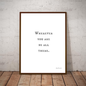 May include: A black and white typography print with the quote "Wherever you are be all there." by Jim Elliot.