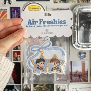 May include: A star-shaped air freshener in clear packaging with a header card reading Air Freshies for the car, home, office or wherever you are! The freshener features two cartoon characters in star frames with a blue ribbon and text reading Get in loser, we're going to the cottage.