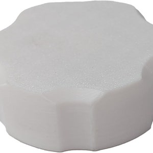 May include: White plastic lid with a starburst shape. The lid has a smooth, textured surface.