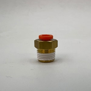 May include: A brass fitting with a threaded base and a bright orange ring on top. The fitting has a hexagonal head and a white band near the base. The object is set against a plain white background.