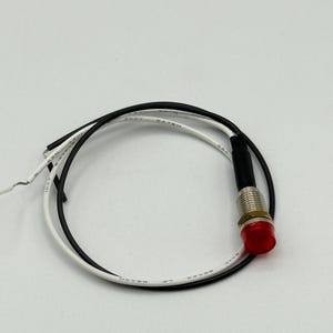 May include: A red LED indicator light with a metal base and black and white wires. The light is circular and emits a bright red glow. The wires are looped and ready for connection.