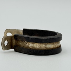 Könnte beinhalten: Eine Metallschelle mit schwarzem Gummieinsatz. Die Schelle hat eine silberne Oberfläche und ein gebogenes Design. Der Text "DG-16" ist auf dem Metallband sichtbar. Die Schelle hat zwei Löcher zur Montage.