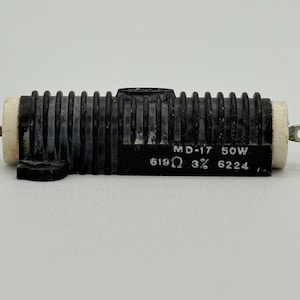 May include: A black MD-17 50W resistor with white ceramic ends and metal terminals. The resistor has a ribbed design and a label with technical specifications: 619Ω 3% 6224.