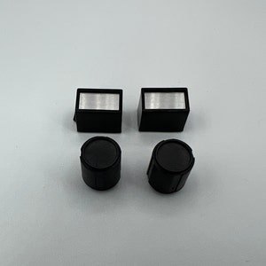 May include: Four black plastic knobs with silver inserts. Two of the knobs are rectangular and two are round.