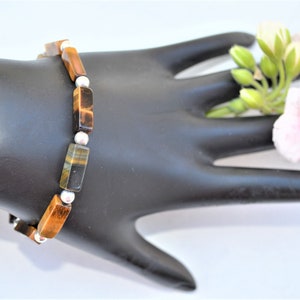 Peut inclure: Un bracelet en pierre de œil de tigre brun et or avec des perles argentées.