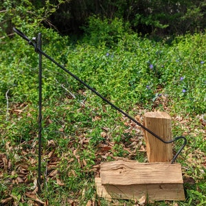 May include: A black metal log lifter with a hook on one end and a pointed end on the other. The lifter is used to move logs for a campfire or fireplace.