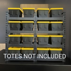 May include: A black metal storage rack with four horizontal shelves, each holding four black plastic bins with bright yellow lids. The rack features a grid-like frame design. White text at the bottom reads: TOTES NOT INCLUDED.