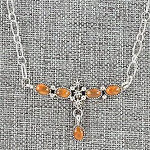 May include: A silver necklace with a pendant featuring a cluster of orange stones. The necklace has a delicate chain and a simple design.