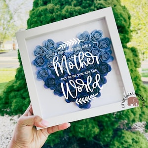 May include: A white framed shadow box with a blue paper flower heart that says "to the world you are a Mother but to us you are the World".