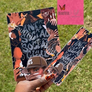 May include: Two rectangular decorative items with a collage design featuring illustrations of people, text that reads "Beautiful & Social Club ATL", and a pink square with text. The items are held against a background of green grass.