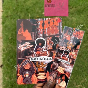 Pode incluir: Dois itens decorativos com ilustrações com tema de outono. Um é um cartão retangular com o texto "Sweater Weather" e "Black Girl Reads". O outro é um marcador com imagens e texto semelhantes. Um quadrado rosa com um logotipo de borboleta no fundo.
