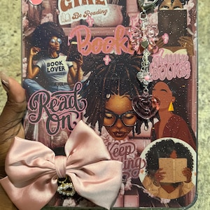 May include: A pink and clear tablet case with a bow and charm. The case features images of Black women, the words "Black Girl Be Reading", and other text related to books. A pink bow with a pearl accent is attached to the case.