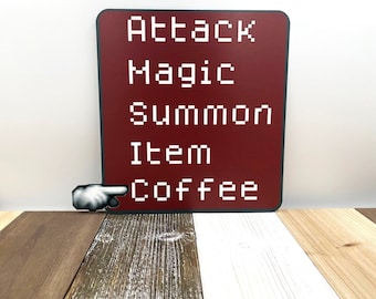 May include: A red square sign with white text that reads "Attack, Magic, Summon, Item, Coffee". A hand with a pointing finger is pointing to the word "Coffee".